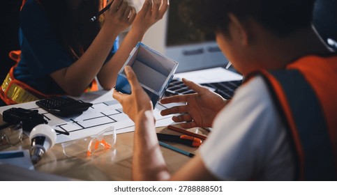 Two technicians inspect server racks in data center with tablet and fiber optic cable. Engineer and specialist discuss maintenance work in data center. Man and woman work together with safety equipmen