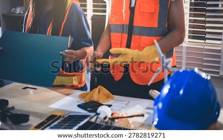 Two technicians inspect server racks in data center with tablet and fiber optic cable. Engineer and specialist discuss maintenance work in data center. Man and woman work together with safety equipmen