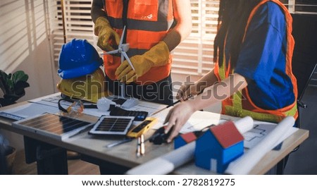 Two technicians inspect server racks in data center with tablet and fiber optic cable. Engineer and specialist discuss maintenance work in data center. Man and woman work together with safety equipmen
