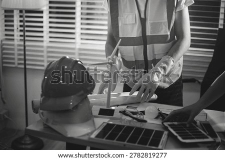 Two technicians inspect server racks in data center with tablet and fiber optic cable. Engineer and specialist discuss maintenance work in data center. Man and woman work together with safety equipmen