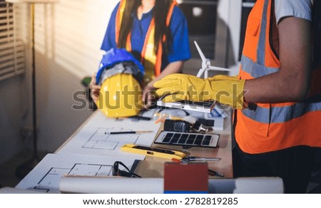Two technicians inspect server racks in data center with tablet and fiber optic cable. Engineer and specialist discuss maintenance work in data center. Man and woman work together with safety equipmen