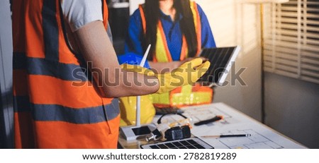 Two technicians inspect server racks in data center with tablet and fiber optic cable. Engineer and specialist discuss maintenance work in data center. Man and woman work together with safety equipmen