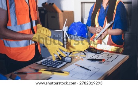 Two technicians inspect server racks in data center with tablet and fiber optic cable. Engineer and specialist discuss maintenance work in data center. Man and woman work together with safety equipmen