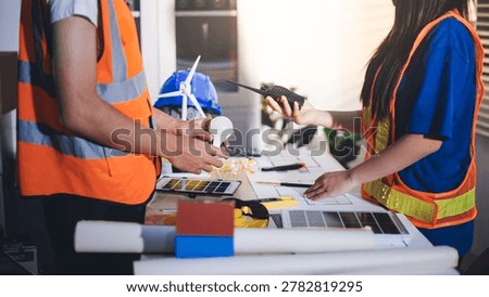 Two technicians inspect server racks in data center with tablet and fiber optic cable. Engineer and specialist discuss maintenance work in data center. Man and woman work together with safety equipmen