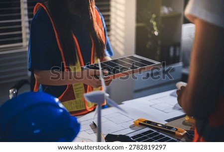 Two technicians inspect server racks in data center with tablet and fiber optic cable. Engineer and specialist discuss maintenance work in data center. Man and woman work together with safety equipmen