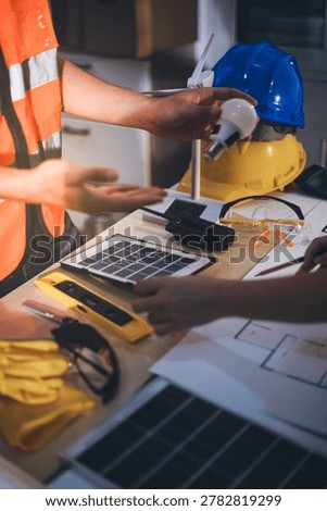 Two technicians inspect server racks in data center with tablet and fiber optic cable. Engineer and specialist discuss maintenance work in data center. Man and woman work together with safety equipmen