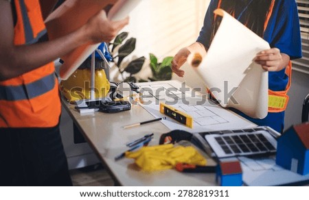 Two technicians inspect server racks in data center with tablet and fiber optic cable. Engineer and specialist discuss maintenance work in data center. Man and woman work together with safety equipmen