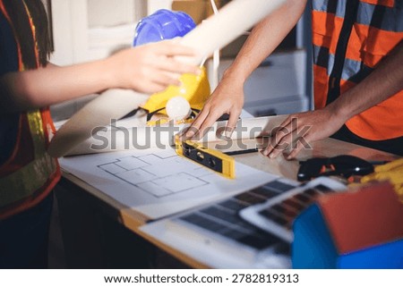 Two technicians inspect server racks in data center with tablet and fiber optic cable. Engineer and specialist discuss maintenance work in data center. Man and woman work together with safety equipmen