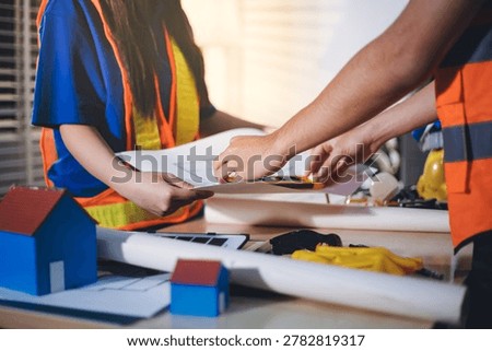 Two technicians inspect server racks in data center with tablet and fiber optic cable. Engineer and specialist discuss maintenance work in data center. Man and woman work together with safety equipmen