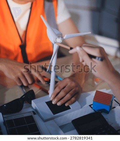 Two technicians inspect server racks in data center with tablet and fiber optic cable. Engineer and specialist discuss maintenance work in data center. Man and woman work together with safety equipmen