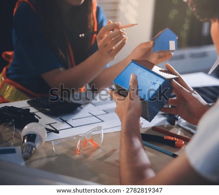 Two technicians inspect server racks in data center with tablet and fiber optic cable. Engineer and specialist discuss maintenance work in data center. Man and woman work together with safety equipmen