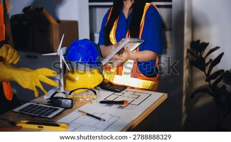 Two technicians inspect server racks in data center with tablet and fiber optic cable. Engineer and specialist discuss maintenance work in data center. Man and woman work together with safety equipmen