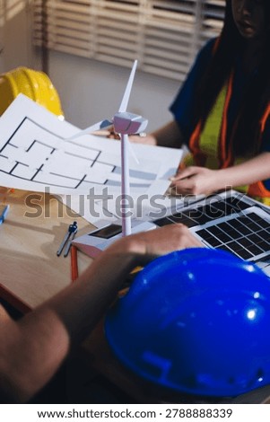 Two technicians inspect server racks in data center with tablet and fiber optic cable. Engineer and specialist discuss maintenance work in data center. Man and woman work together with safety equipmen