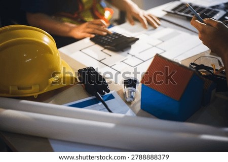 Two technicians inspect server racks in data center with tablet and fiber optic cable. Engineer and specialist discuss maintenance work in data center. Man and woman work together with safety equipmen