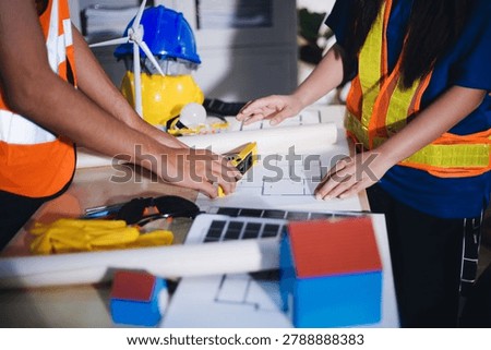 Two technicians inspect server racks in data center with tablet and fiber optic cable. Engineer and specialist discuss maintenance work in data center. Man and woman work together with safety equipmen