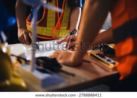 Two technicians inspect server racks in data center with tablet and fiber optic cable. Engineer and specialist discuss maintenance work in data center. Man and woman work together with safety equipmen