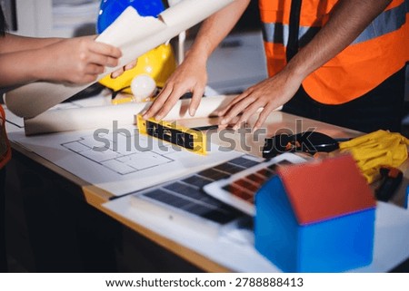 Two technicians inspect server racks in data center with tablet and fiber optic cable. Engineer and specialist discuss maintenance work in data center. Man and woman work together with safety equipmen