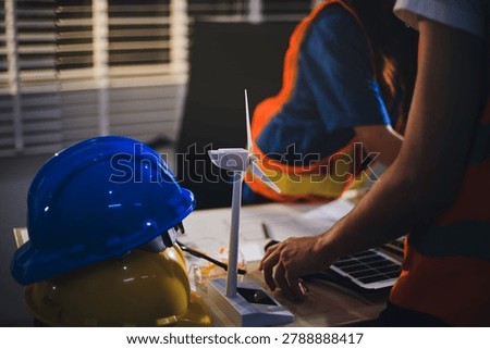 Two technicians inspect server racks in data center with tablet and fiber optic cable. Engineer and specialist discuss maintenance work in data center. Man and woman work together with safety equipmen