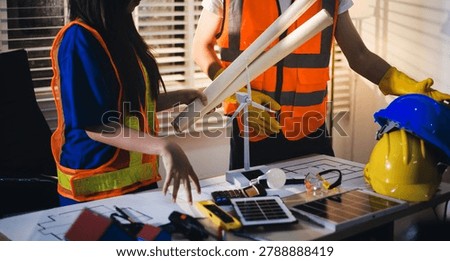 Two technicians inspect server racks in data center with tablet and fiber optic cable. Engineer and specialist discuss maintenance work in data center. Man and woman work together with safety equipmen