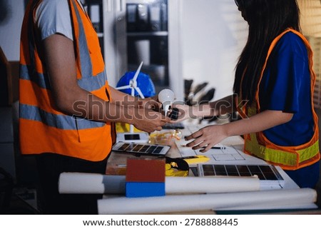 Two technicians inspect server racks in data center with tablet and fiber optic cable. Engineer and specialist discuss maintenance work in data center. Man and woman work together with safety equipmen