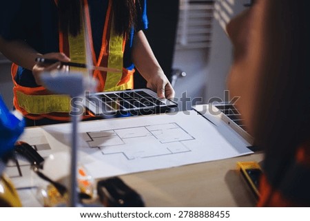 Two technicians inspect server racks in data center with tablet and fiber optic cable. Engineer and specialist discuss maintenance work in data center. Man and woman work together with safety equipmen
