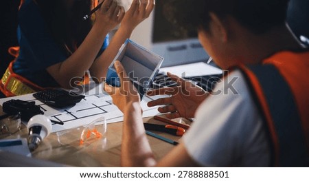 Two technicians inspect server racks in data center with tablet and fiber optic cable. Engineer and specialist discuss maintenance work in data center. Man and woman work together with safety equipmen