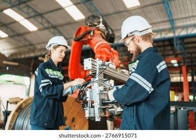 Two technicians in safety gear work together on complex machinery, highlighting teamwork and industrial innovation