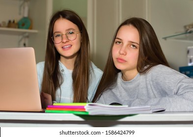 Two Teen Girls Do Homework With The Help Of The Laptop. Too Much Information Can Bring Fatigue And Exhaustion. The Concept Of Communication And Navigation, The Internet, Social Network.