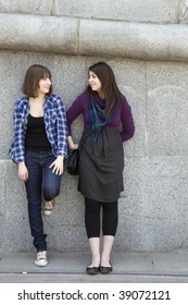 Two Teen Girls Talking At Stone Wall