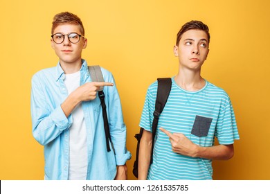 Two Teen Guys Point At Each Other With Their Thumbs, Blame And Do Not Want To Admit Their Guilt