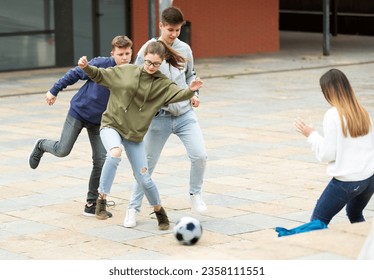 Two teenage boys and two cute girls play ball near the school building - Powered by Shutterstock