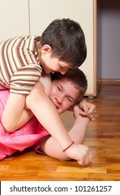 Two Teenage Boys Wrestling On Wooden Floor.