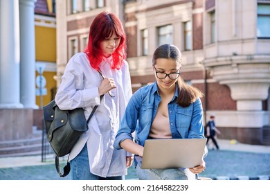 Two Teenage Female Students Using Outdoor Laptop, City Street Background