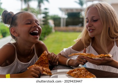 Two Teenage Girls Eating Fast Food And Laughing.