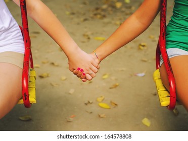 Two Teenage Girls Holding Hands On Beautiful Autumn Day.