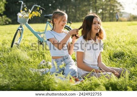 Similar – Foto Bild Zwei Teenager-Mädchen verbringen Zeit auf grünem Rasen im Park, flechten Zöpfe und Schwänze für einander, genießen Sommer und Ferien