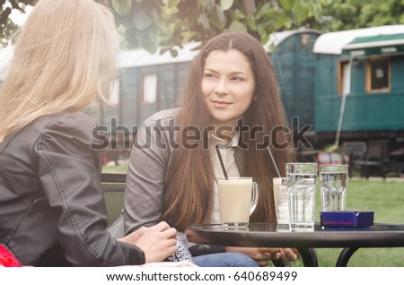 Two teenage girls talking in nature with coffee