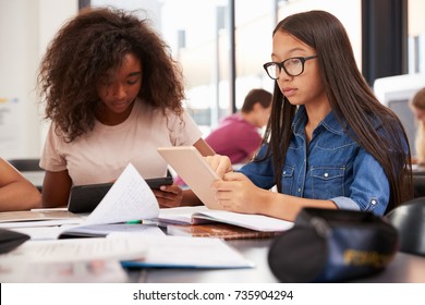 Two teenage schoolgirls using tablet computers in class