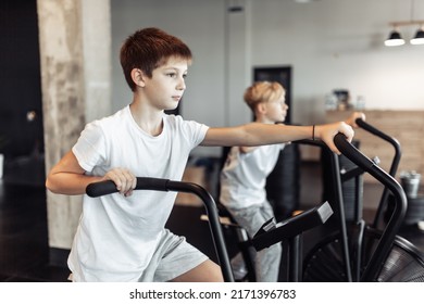 Two teenager boys are doing exercise with airbike in the gym. Cardio, strength training, fitness concept - Shutterstock ID 2171396783