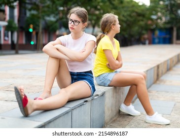 Two Teenager Girls Quarreling While Sitting In Urban Park.