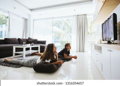 Two Teenagers Watching Tv While Relaxing On Couch In Living Room