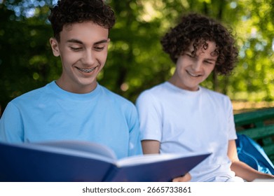 Two teens in the park preparing for the lessons and reading a book