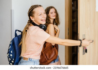 Two teens student girls friends with backpacks opening door of classroom at school. Back to school concept. - Powered by Shutterstock