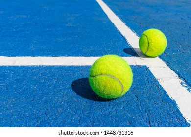 Two tennis balls on a blue tennis court with white marking lines. White sideline, concret, hard court. - Shutterstock ID 1448731316