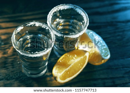 Two tequila and lime slices on a wooden background in the bar