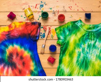 Two Tie Dye T-shirts And A Fabric Painting Kit On A Wooden Table. White Clothes Painted By Hand. Flat Lay.