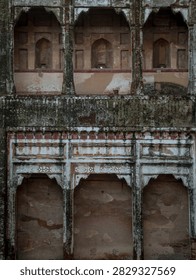 A two tiered weathered facade featuring scalloped cusped arches and ancient plaster on historic Mughal architecture.
