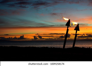 Two tiki torches burn against a Hawaiian sunset - Powered by Shutterstock