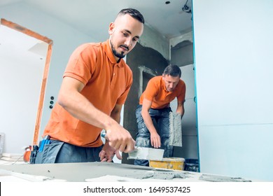  Two Tilers Installing Large Format Tile On Wall. Home Indoors Renovation,education 
Training Teaching Concept