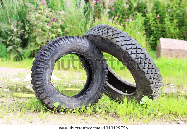 two tires from the car lie on the green grass. The\
concept of pollution of the environment and industrial industry\
that attacks nature